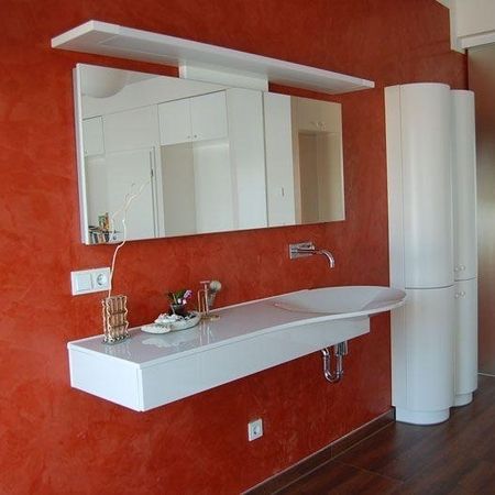 Waschbecken mit Spiegel an einer roten Wand