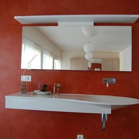 Waschbecken mit Spiegel an einer roten Wand