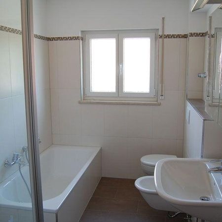 Weißes Badezimmer mit Dusche und Badewanne