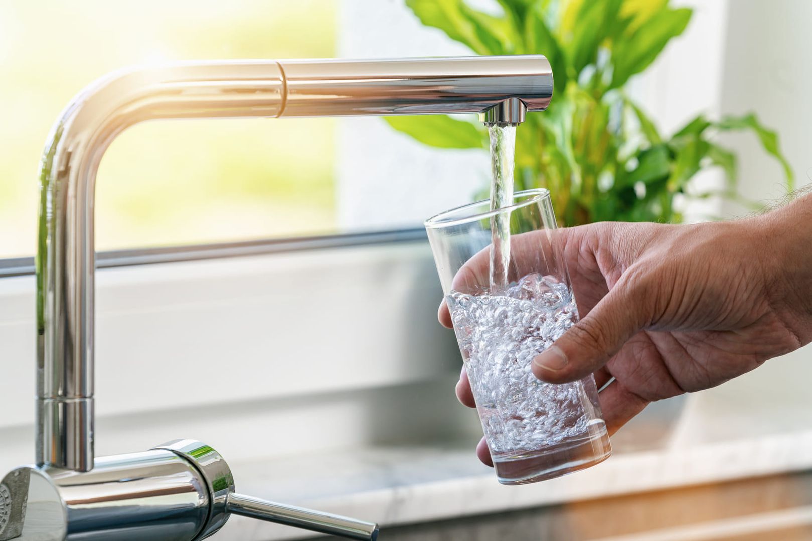 Füllen eines Glases mit Wasser aus dem Edelstahl-Küchenhahn